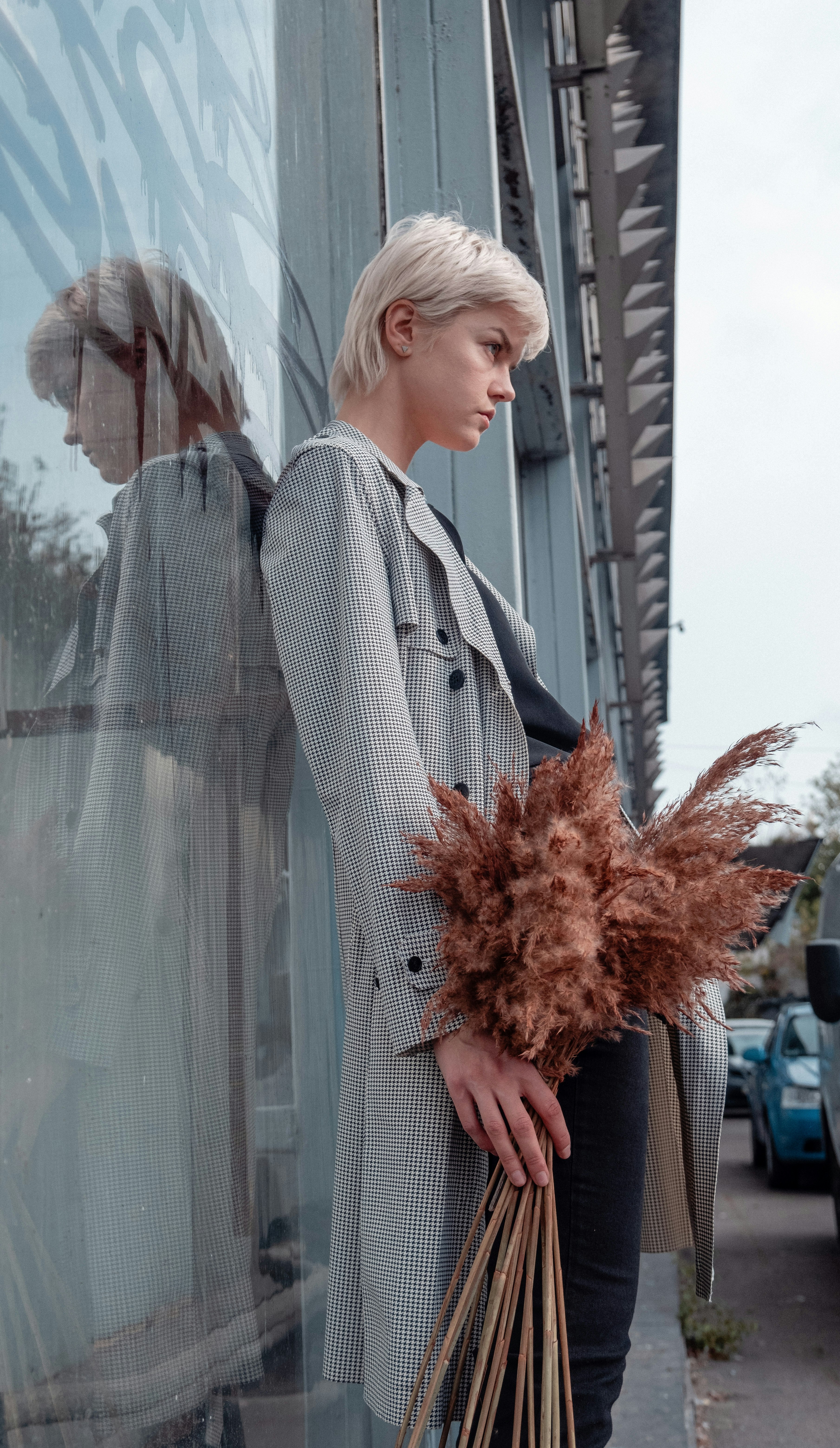 woman in gray coat standing beside glass wall